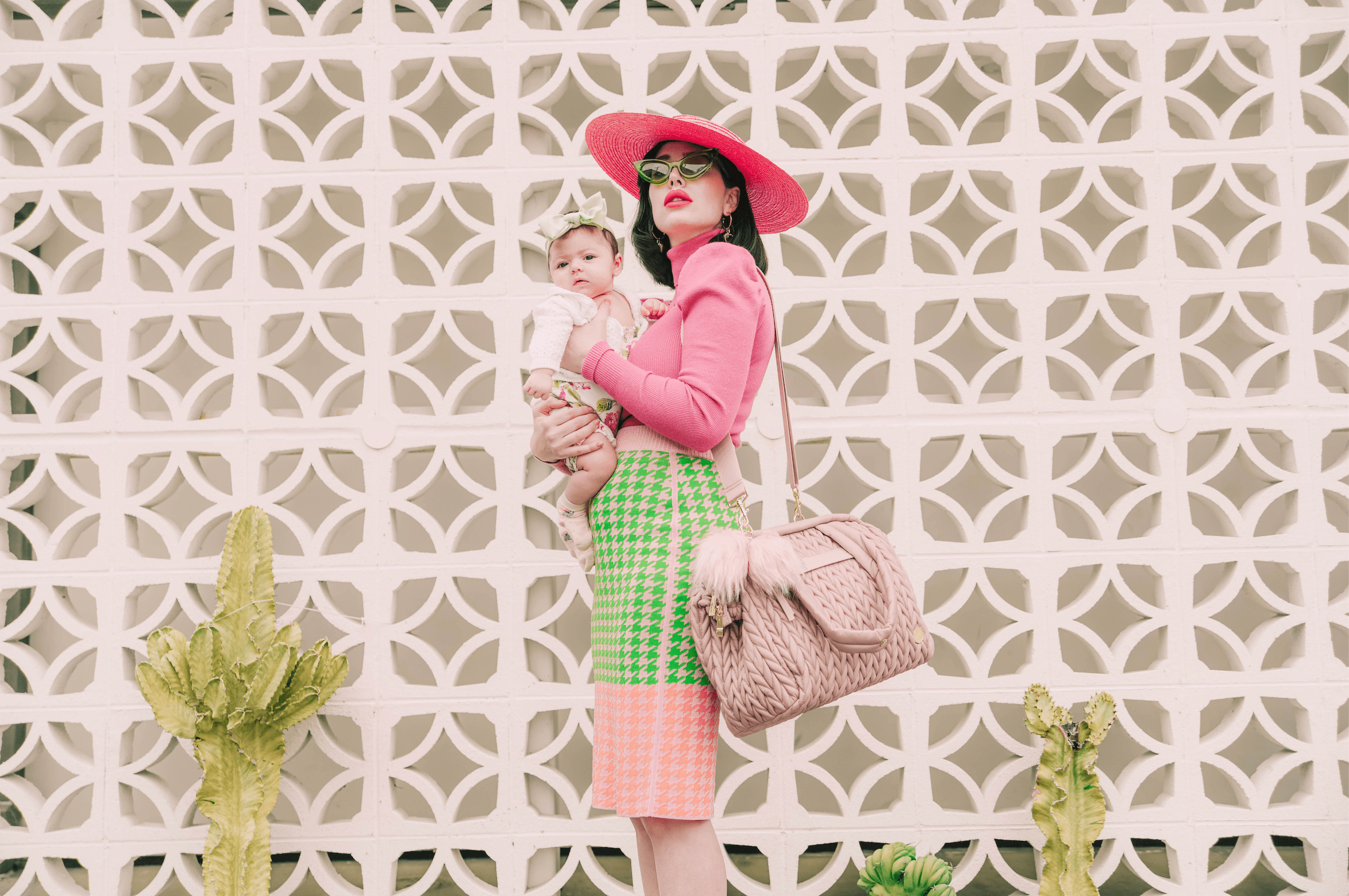 Amy wears her HAPP Paige Carryall in Dusty Rose while carrying her baby in a matching pink-and-green outfit.