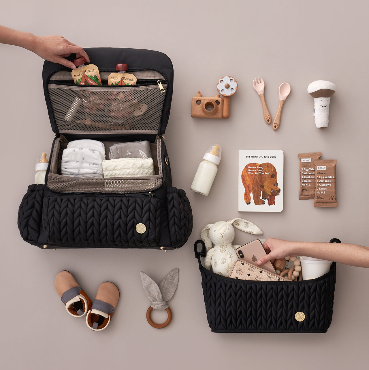 Levy Backpack Black shown open and packed; a hand reaches into the mesh pocket to grab a pouch. Matching Stroller Organizer Black also shown packed, with a hand reaching into the zipper pocket for a phone.