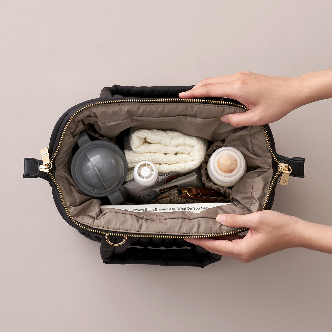 Top-down view of structured mini diaper bag, showing wide Mary Poppins opening, the bag packed with baby items.