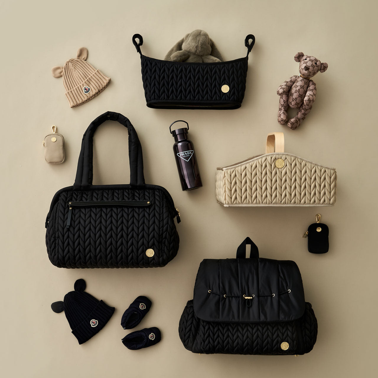 HAPP Neutrals collection, including Levy Backpack Black, Paige Carryall Black, Stroller Organizer Black, Diaper Caddy Beige, and Clip-on Pouches in Beige and Black, arranged with matching baby items.