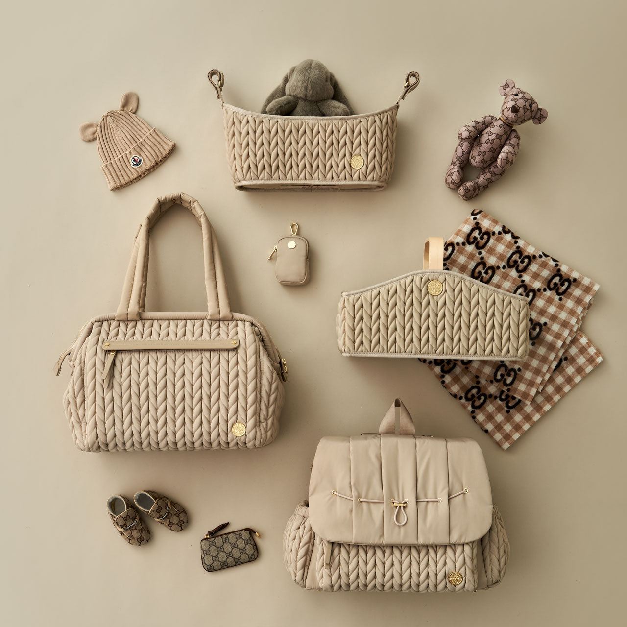 HAPP Beige collection, including Levy Backpack, Paige Carryall, Stroller Organizer, Diaper Caddy, and Clip-on Pouch, arranged together with matching baby items.