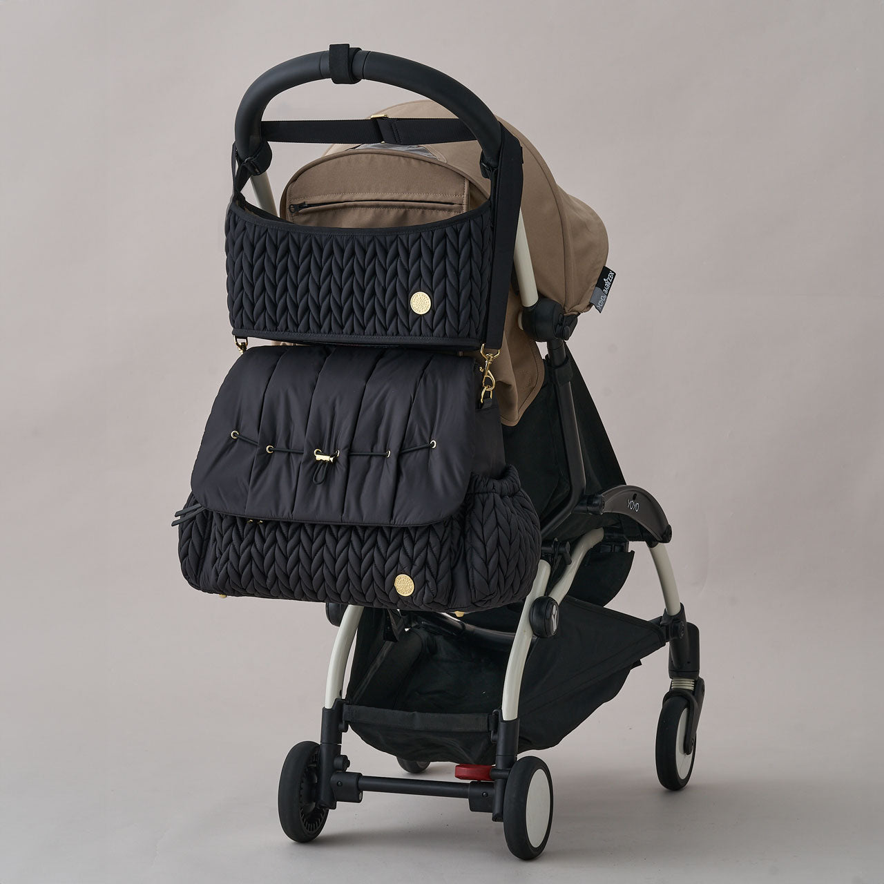 HAPP Stroller Organizer and Levy Backpack in Black shown attached to a black and beige stroller, with the organizer hanging neatly above the diaper bag.