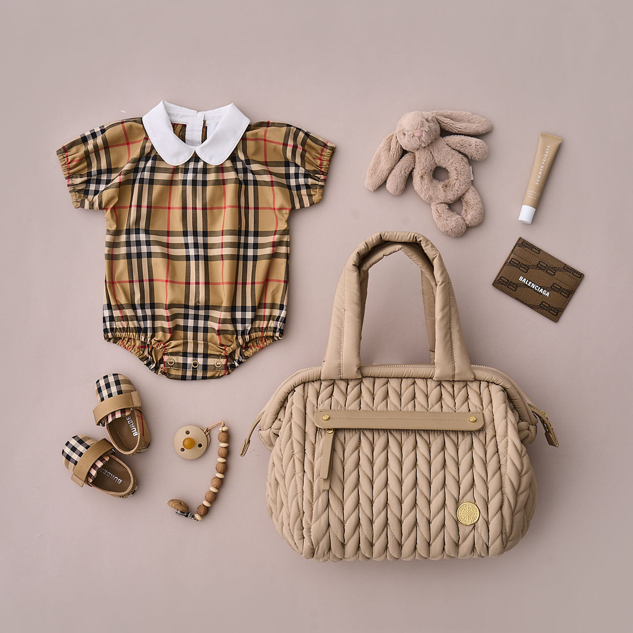 Flat-lay of the Paige Mini Beige from the front, showing carry handles and front mom pocket, alongside matching baby items.