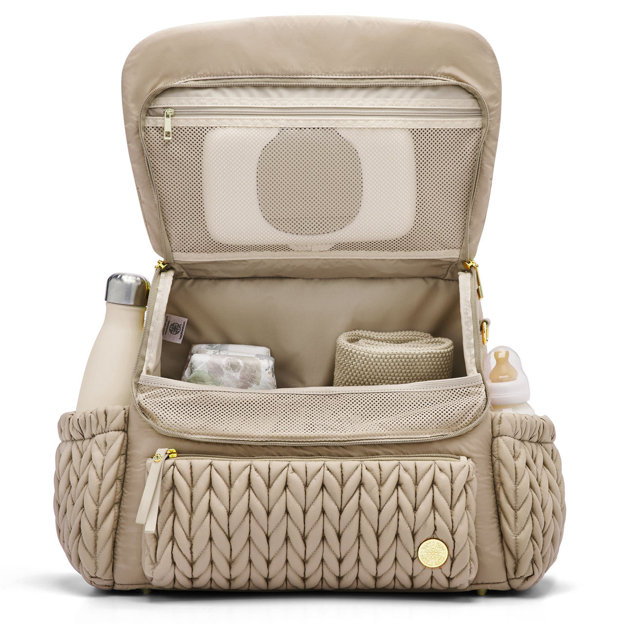 Levy Backpack Beige standing upright with the flap open to show the interior mesh pocket and 4 interior pockets. Bottles in the exterior bottle pockets. The bag is lined with beige fabric.