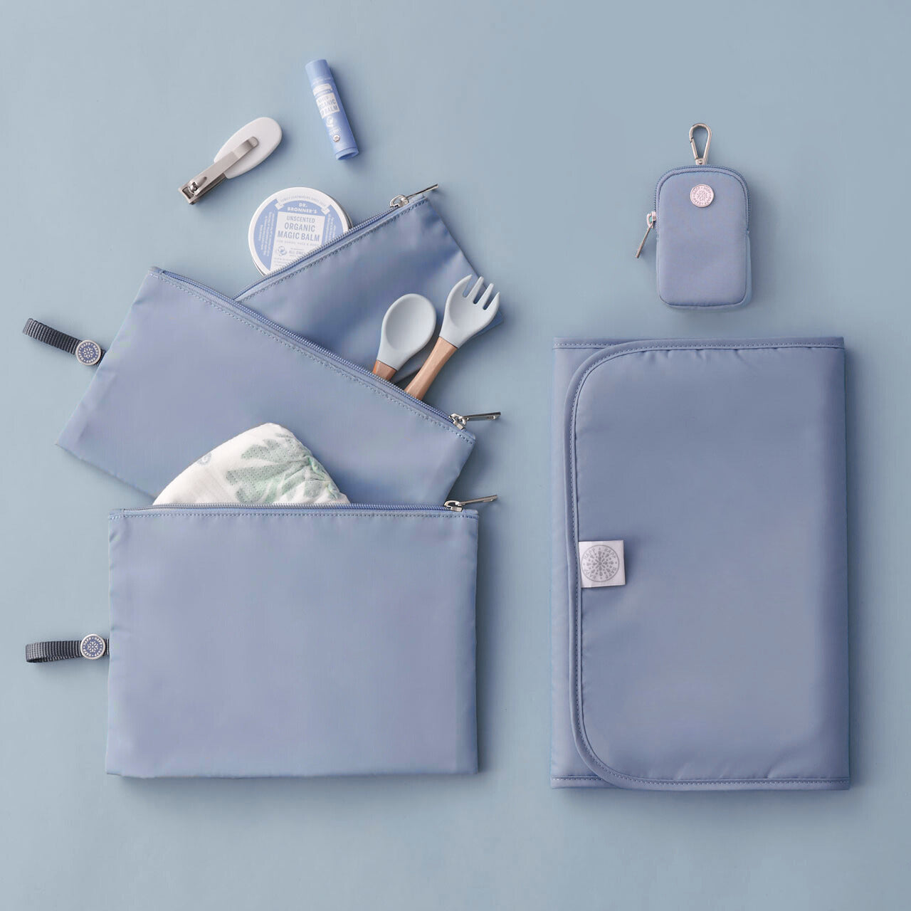 Blue memory foam changing pad, folded lying flat next to matching HAPP Packing Pouches and Clip-On Pouch.
