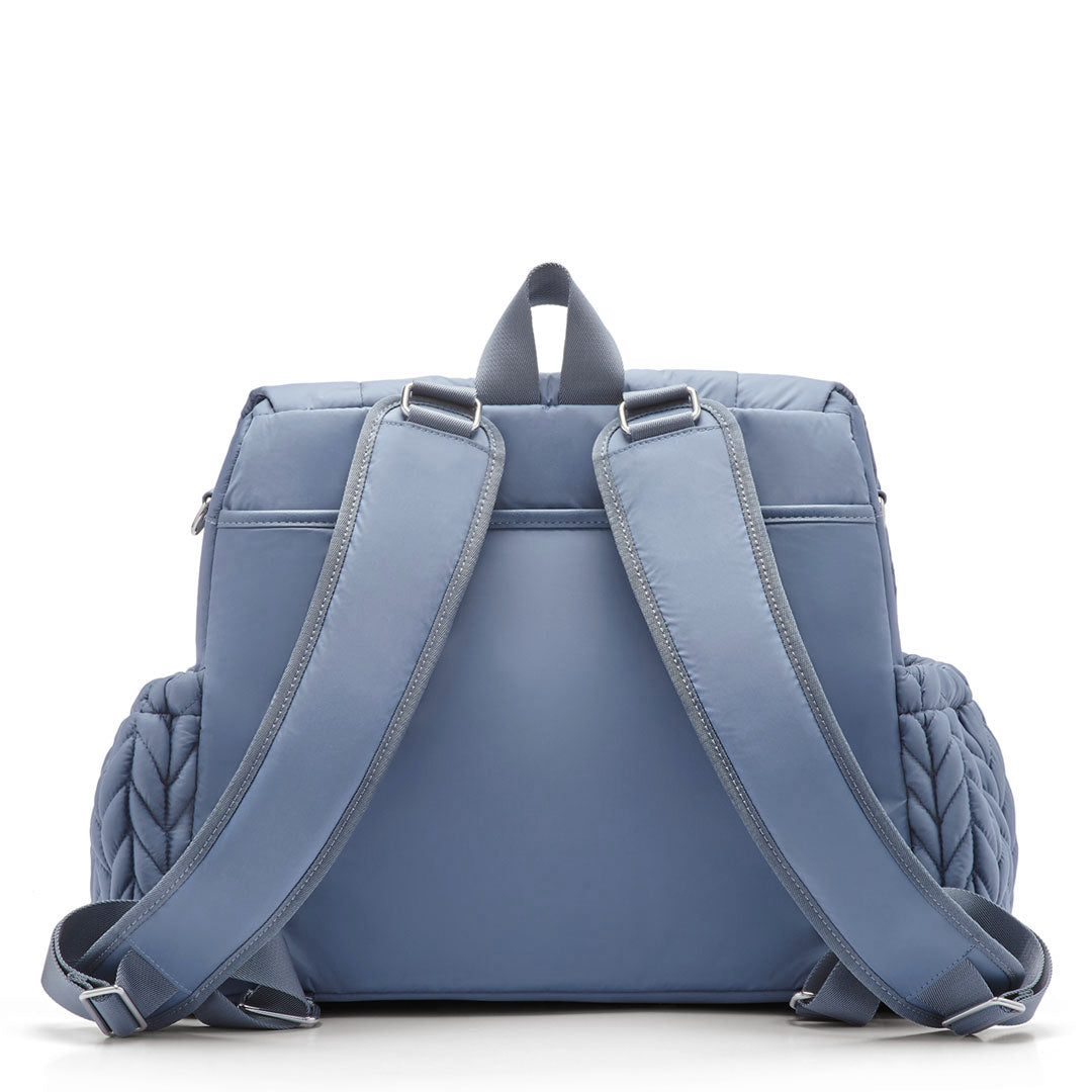 Levy Backpack Ash Blue from the back, standing upright. Shows wide, padded backpack straps, top carry handle, back magnetic pocket, and side bottle pockets.
