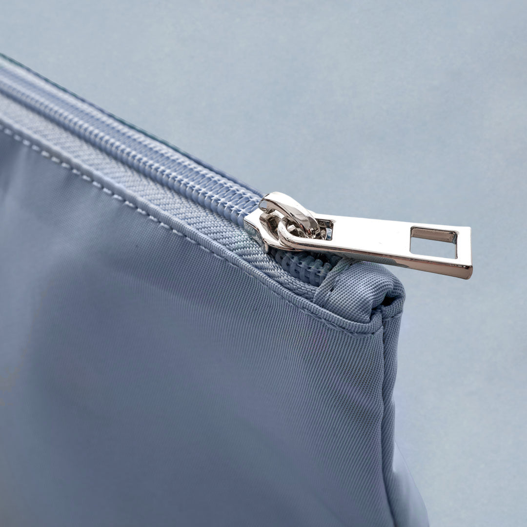 Closeup of silver zipper pull and blue zipper on blue expandable packing pouches.