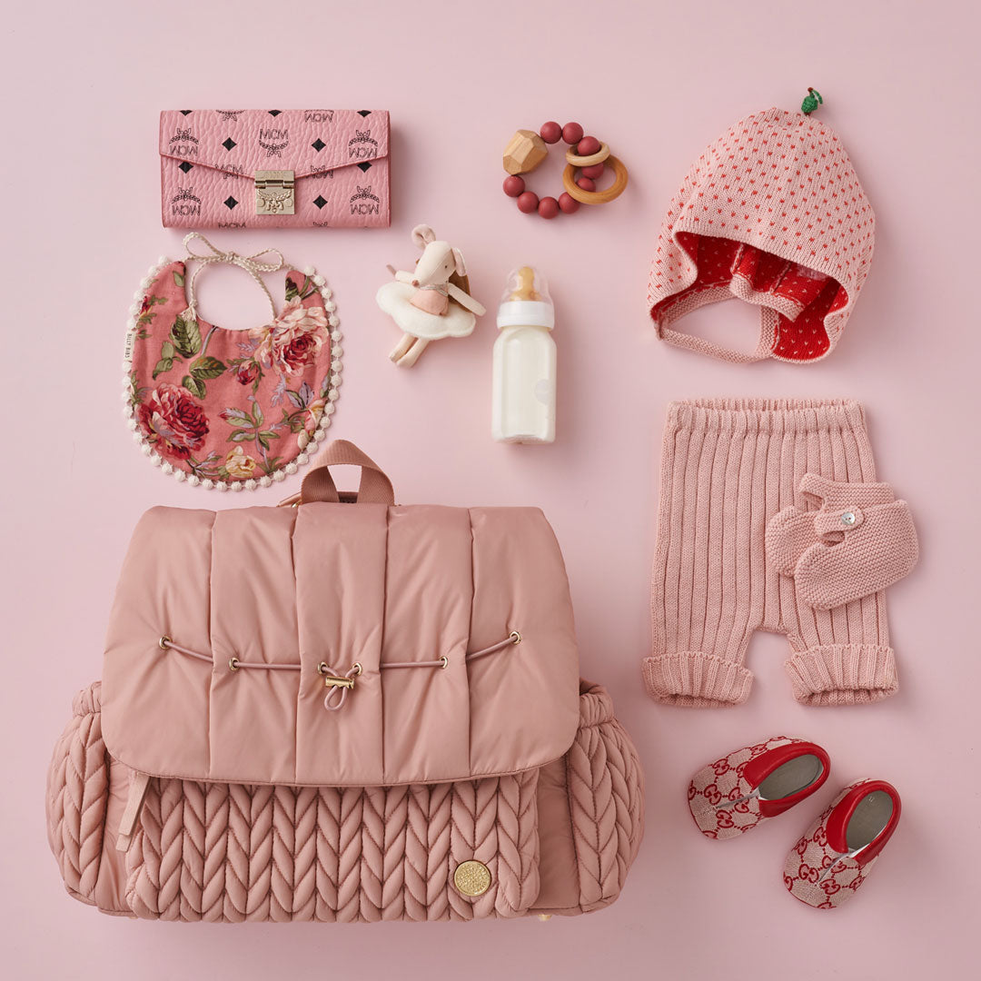 Levy Backpack Dusty Rose lying flat and closed, arranged with matching fashionable mom and baby items.