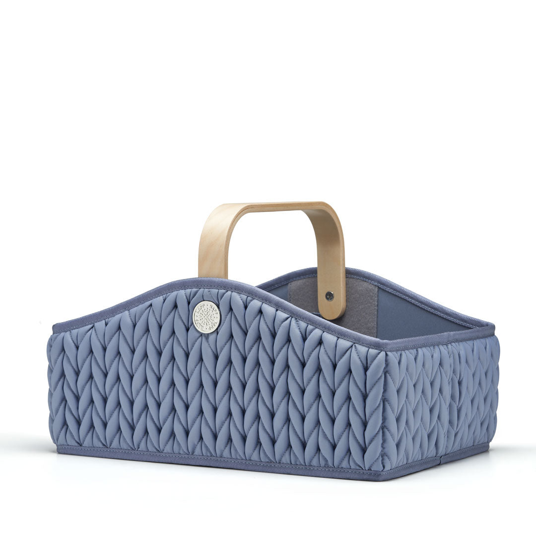Blue diaper caddy shown at a 3/4 angle, empty and standing upright. Shows quality construction, 3D quilted herringbone, wooden handle, and silver hardware details.