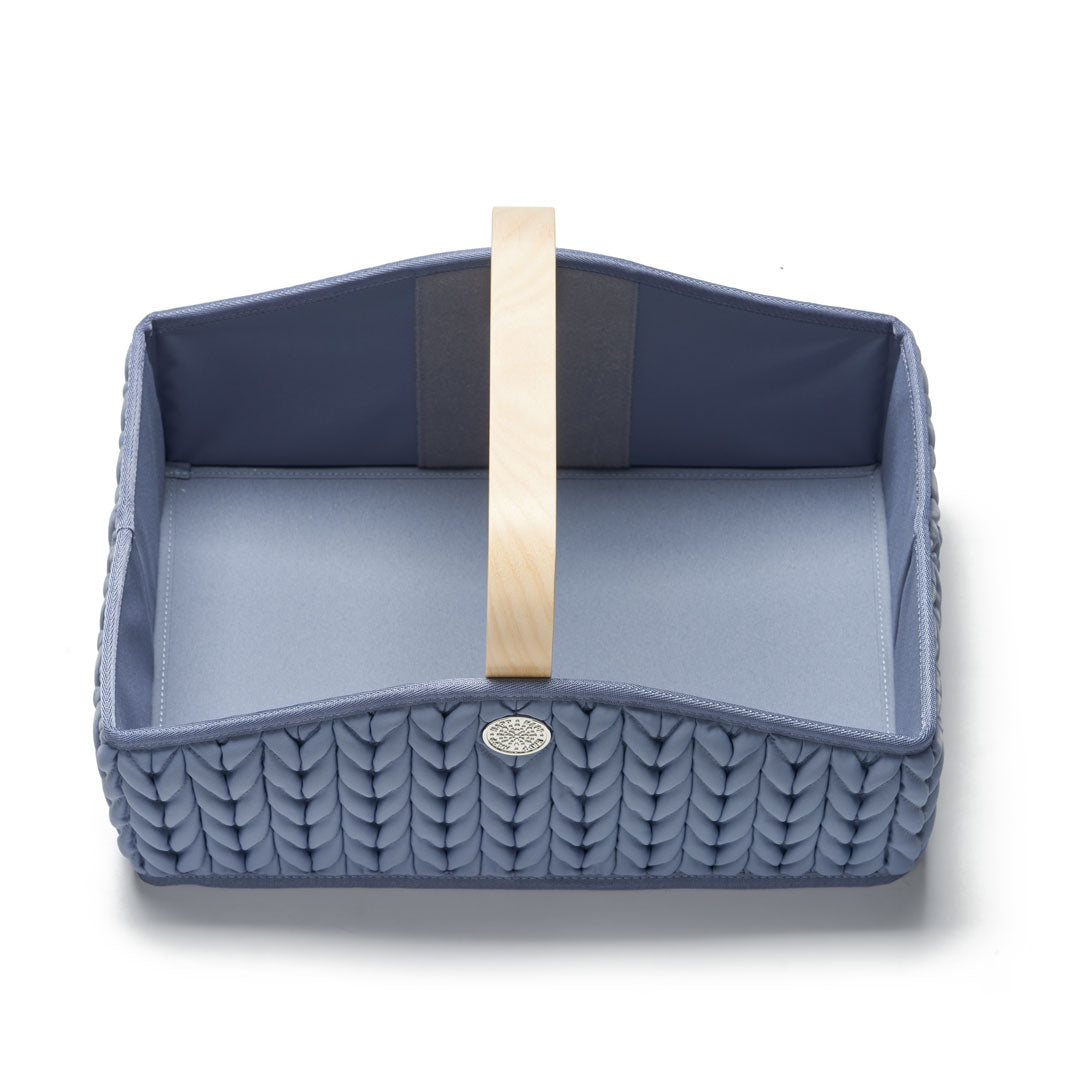 Blue diaper caddy from above, empty without divider pockets, showing wooden handle, sturdy yet lightweight construction, 3D herringbone fabric, and silver hardware detail.