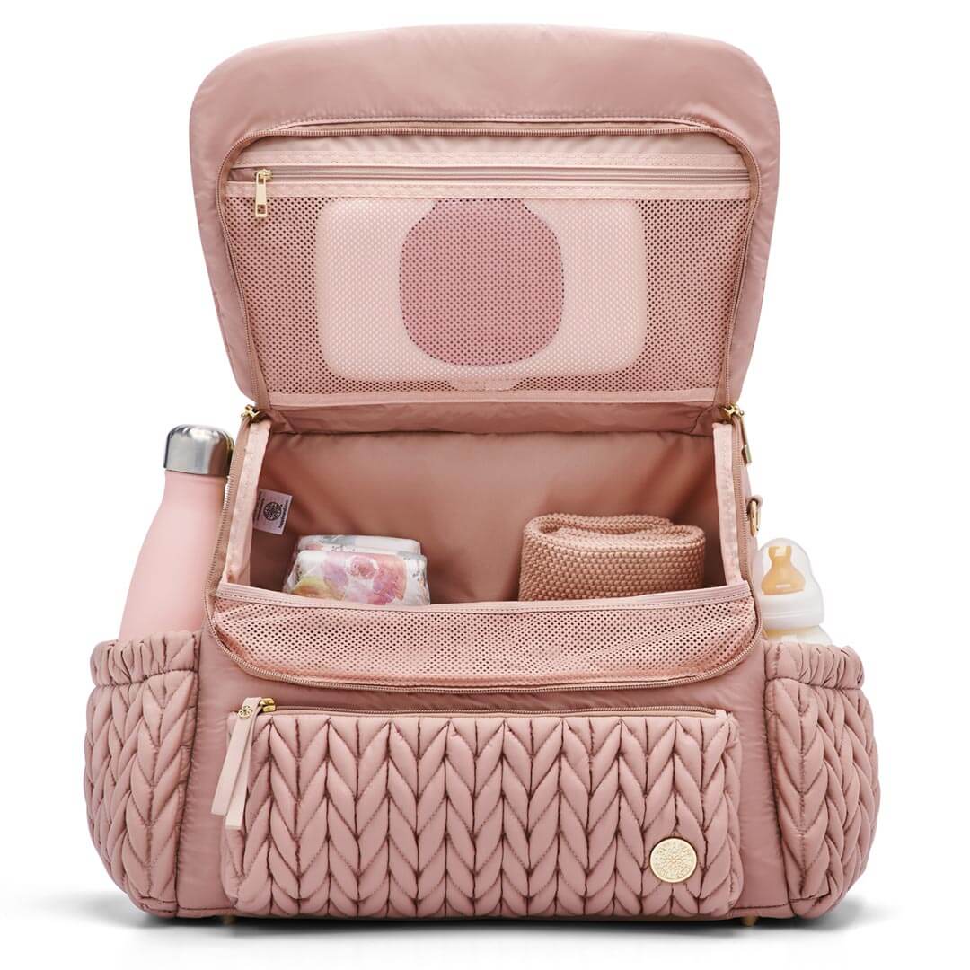 Levy Backpack Dusty Rose standing upright with the flap open to show the interior mesh pocket and 4 interior pockets. Bottles in the exterior bottle pockets. The bag is lined with Rose fabric.