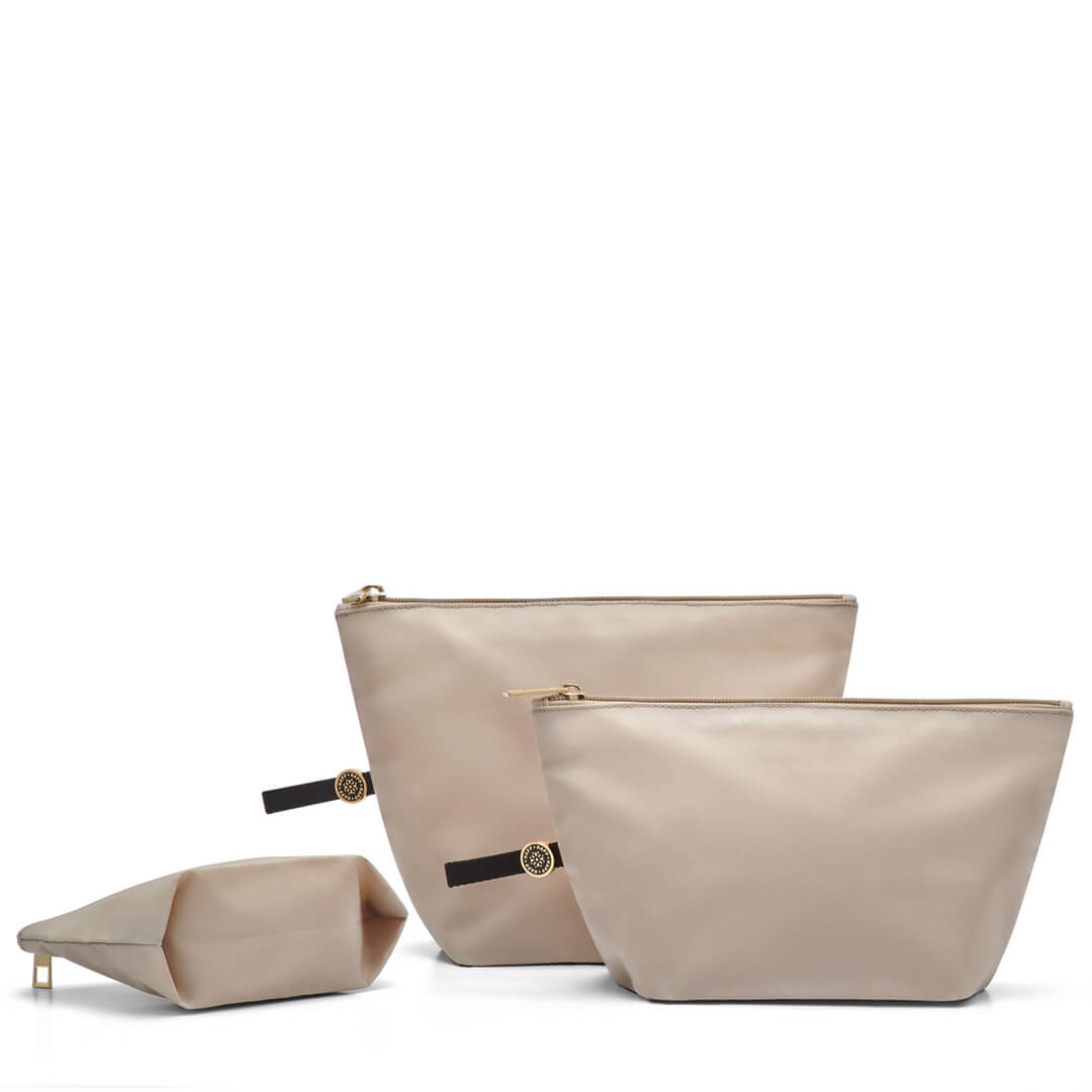 A set of three beige packing pouches of varying sizes, made of a solid material with zipper closures and pull-tab loops, displayed against a white background.