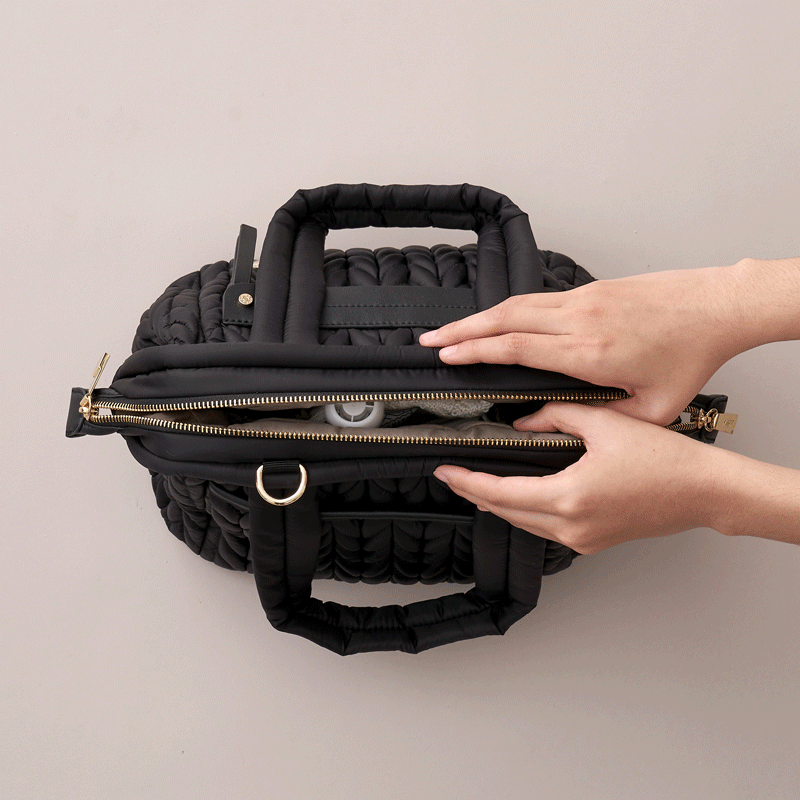 Moving GIF of hands opening and closing the Paige Mini Black, showing the wide Mary Poppins opening while bag is packed with baby items.