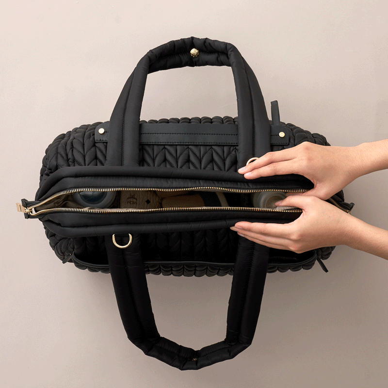 Moving GIF of two hands opening and closing a fully-packed Paige Carryall Black, showing the wide Mary Poppins style opening.
