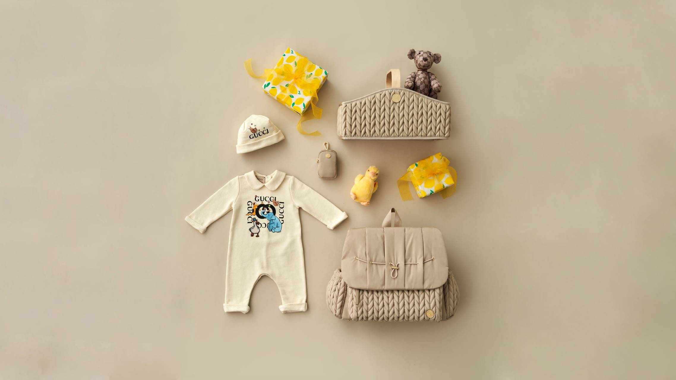 HAPP Brand Beige Herringbone Collection with Levy Backpack, Diaper Caddy, and Clip-on Pouch laid flat on their backs with spring-themed baby items and accessories on a beige background.